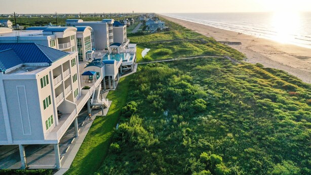A coastal hotel with multiple buildings, a swimming pool, and a beach view.