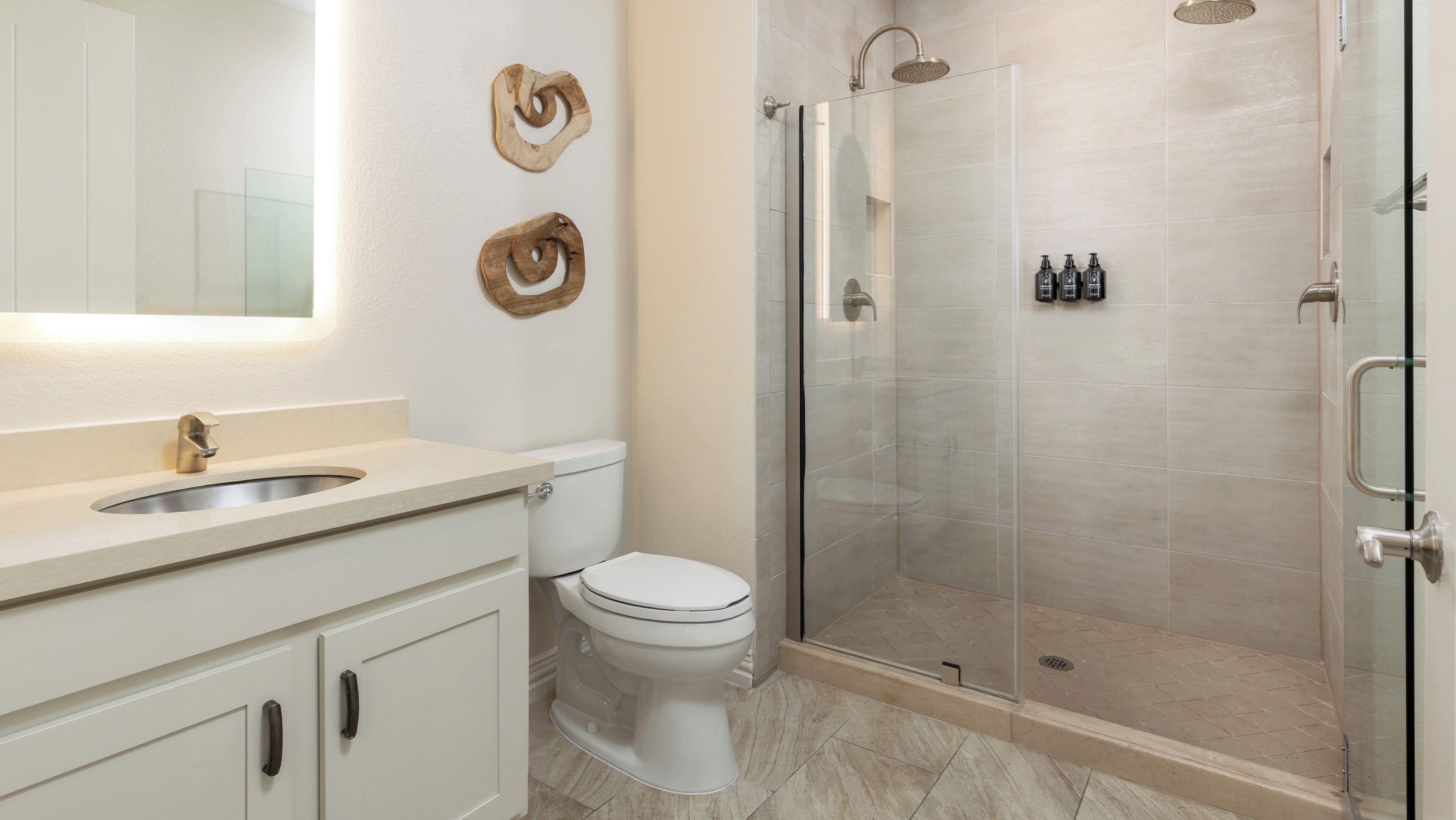 Un baño moderno con lavamanos, inodoro y ducha con mampara de vidrio.