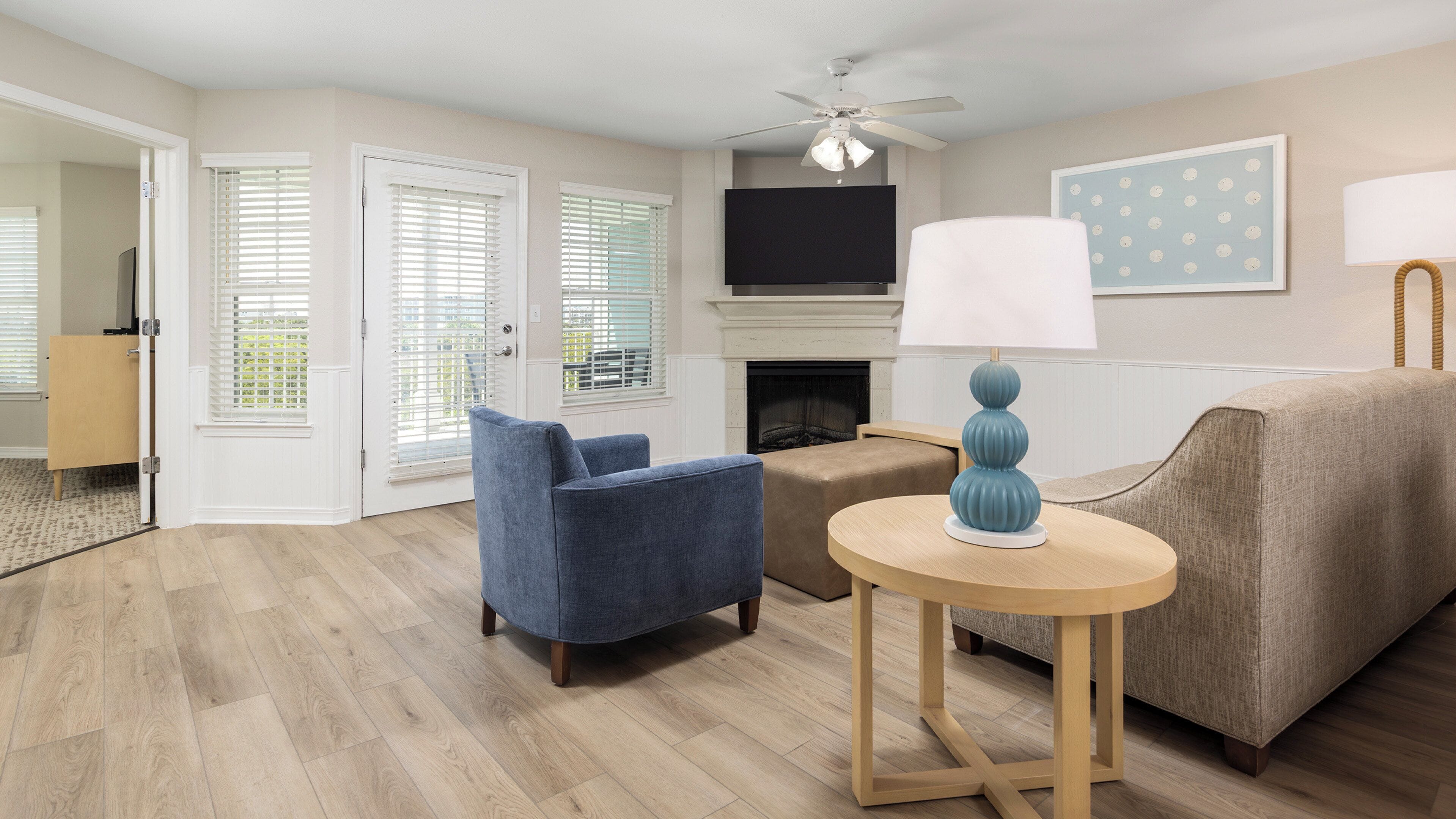 A living room with a fireplace, a television mounted above it, and a ceiling fan.