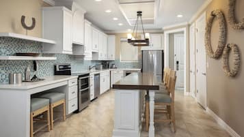 A modern kitchen with white cabinetry, a large island, and a breakfast bar.
