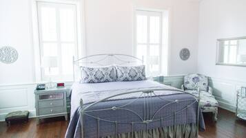 A neatly arranged bedroom with a metal bed frame, a bedside table with a lamp, and a chair.