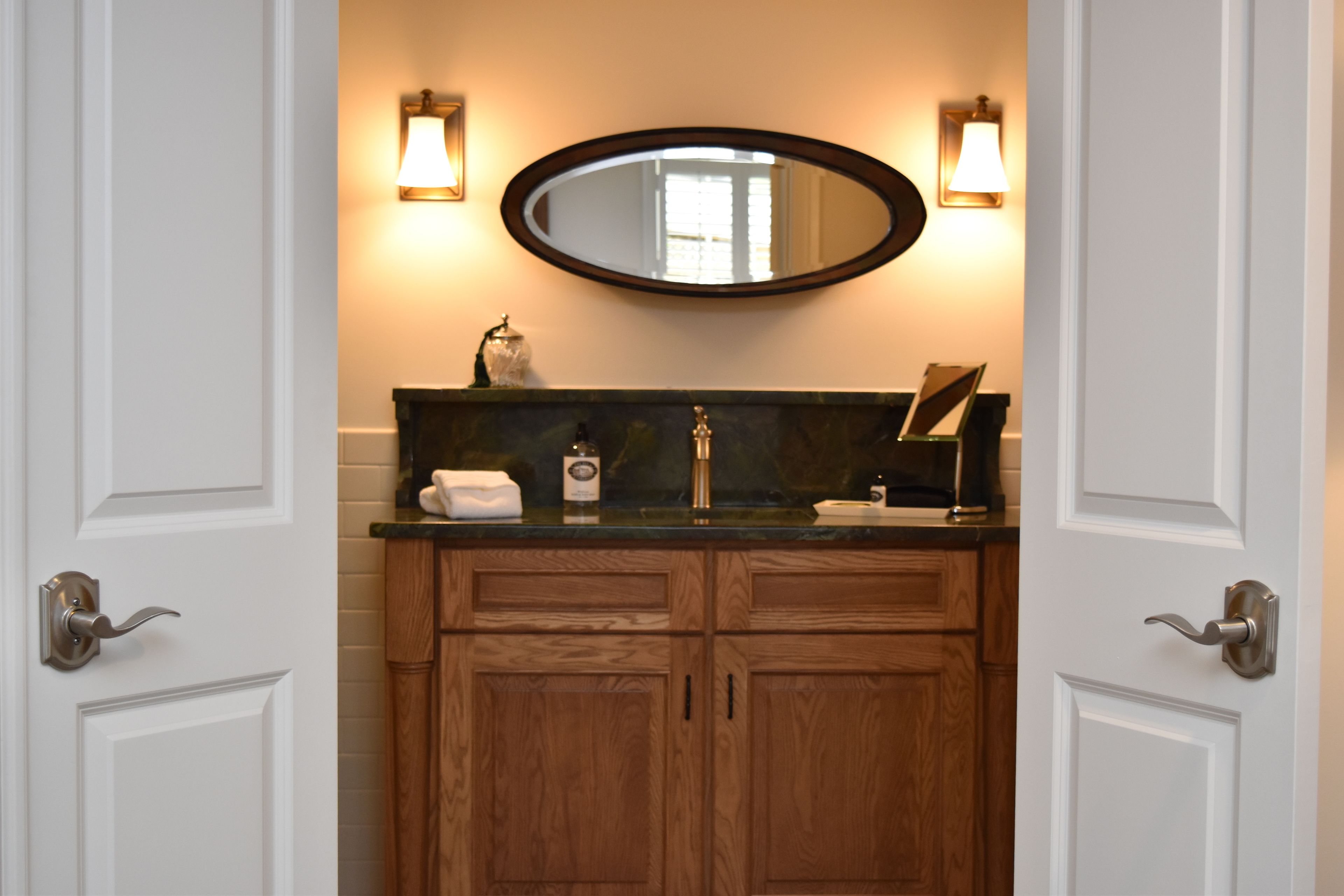 Une salle de bain avec des meubles en bois, un miroir et deux appliques murales.