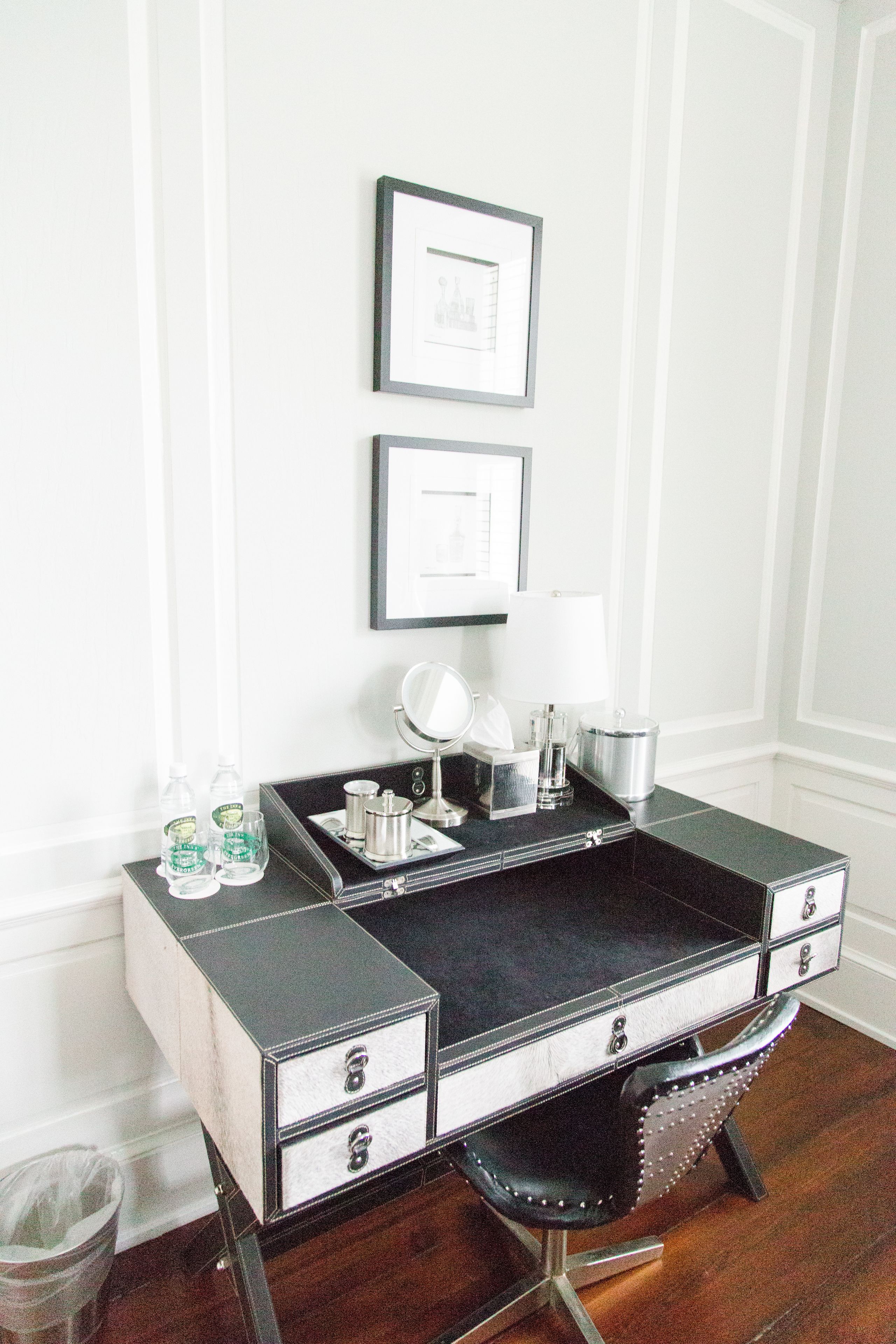 A compact, modern vanity with a black and white color scheme, featuring a mirror, a small sink, and a few toiletries.