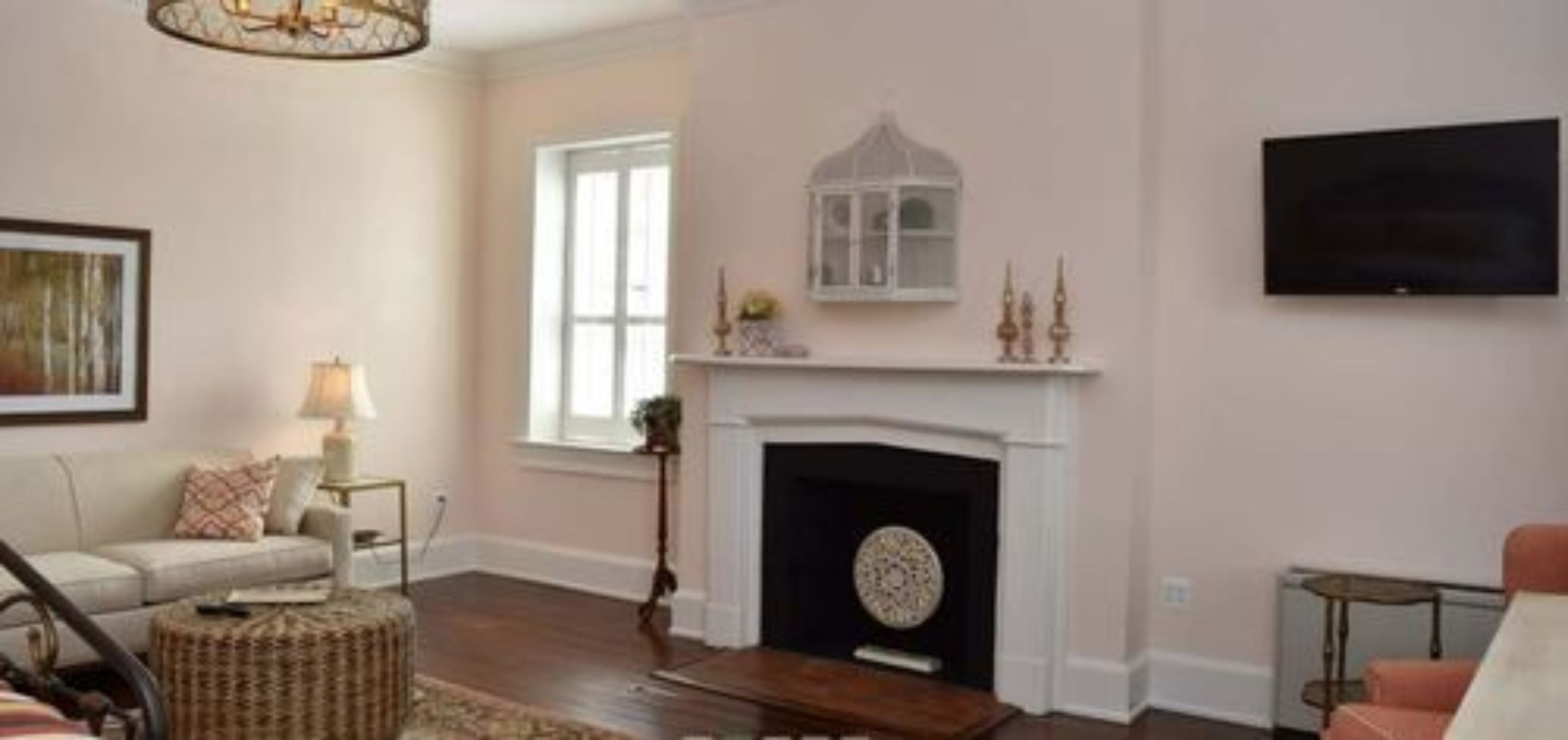 A living room with a fireplace, a sofa, a television, and a window.