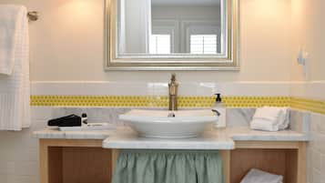A bathroom with a white sink, a mirror with a gold frame, and a wooden vanity with shelves.