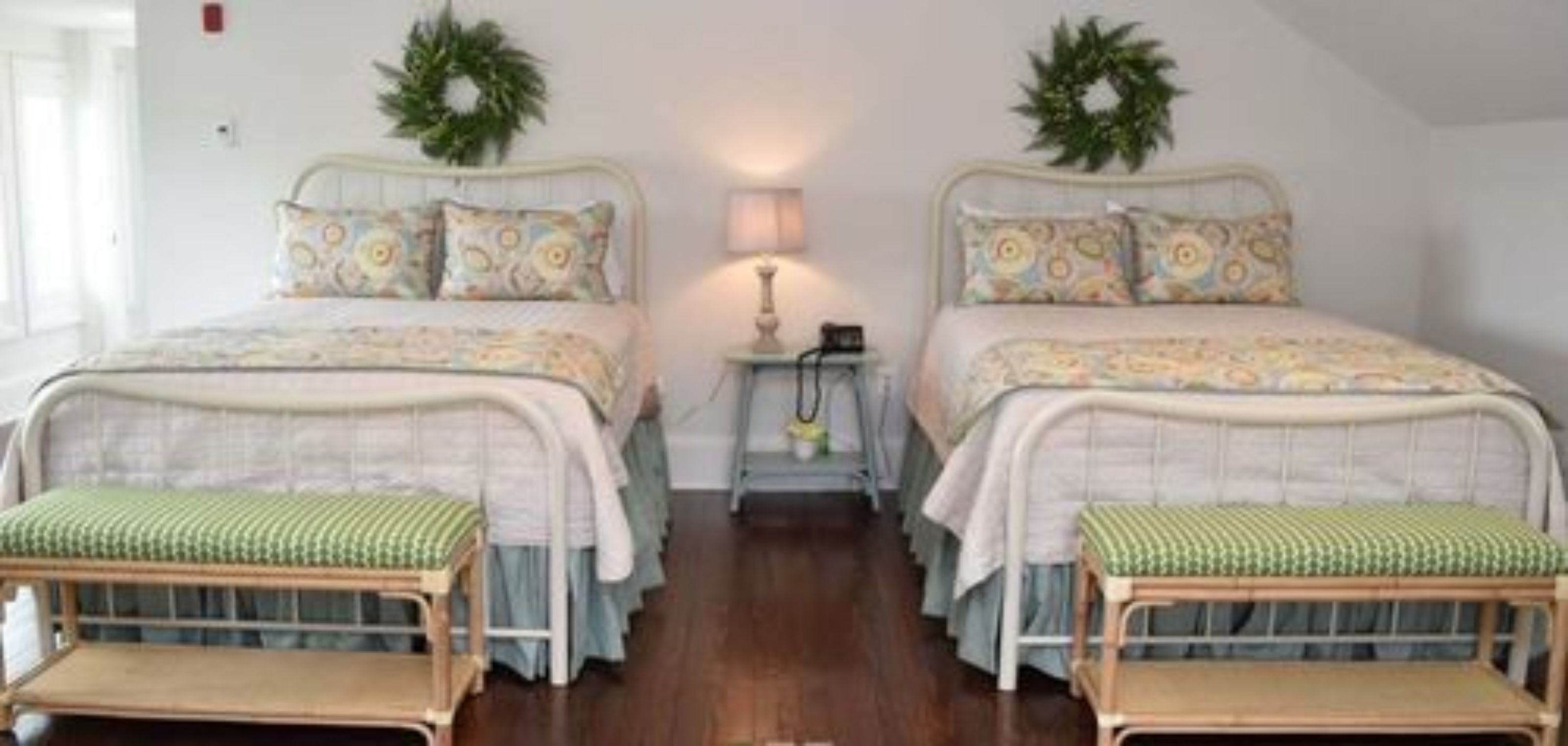 Un dormitorio con dos camas, cada una con cabecero y almohada a juego. Hay dos mesitas de noche con lámparas y una alfombra pequeña entre las camas.