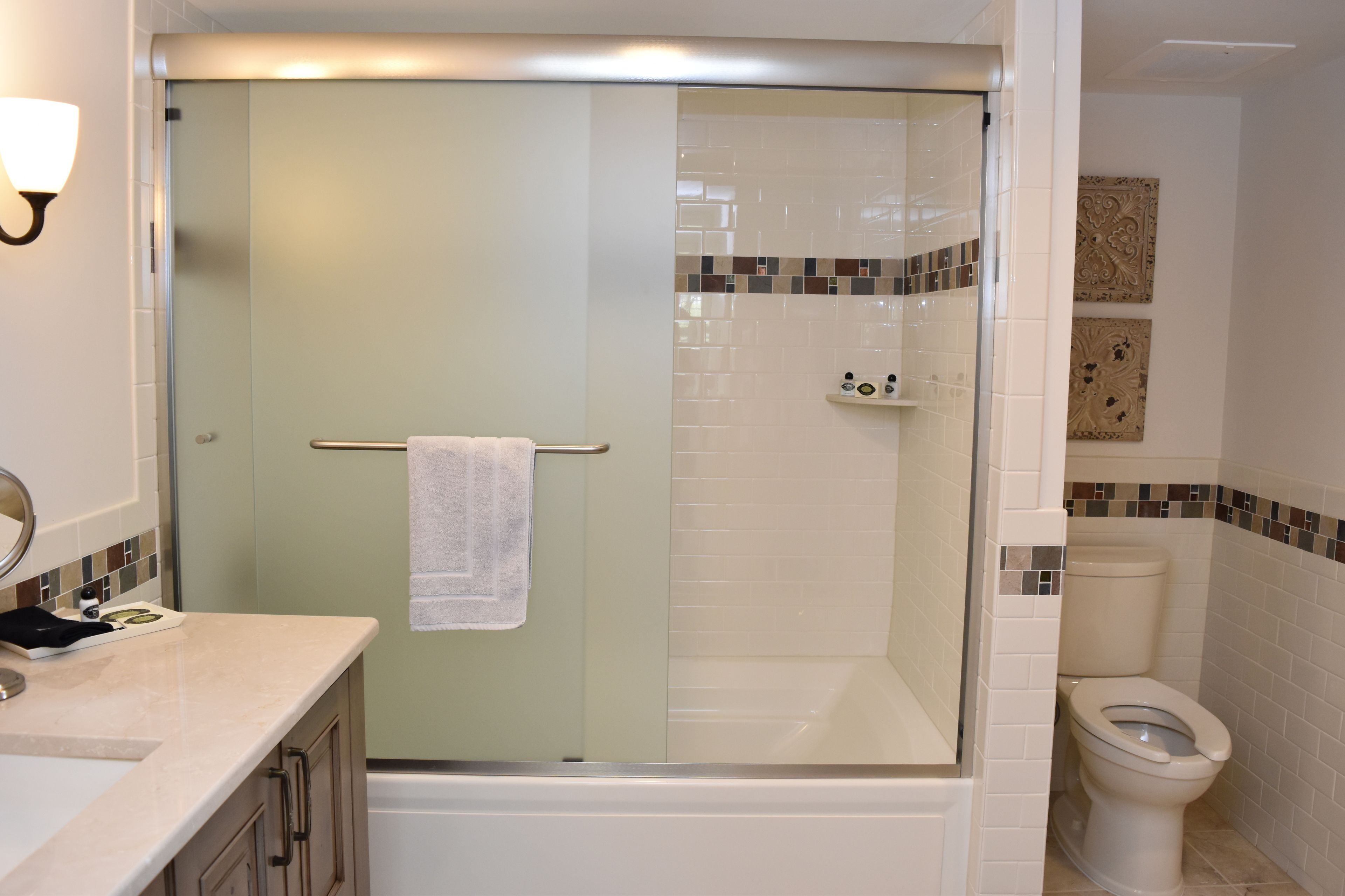 A bathroom with a glass-enclosed shower, a toilet, and a sink with a mirror.