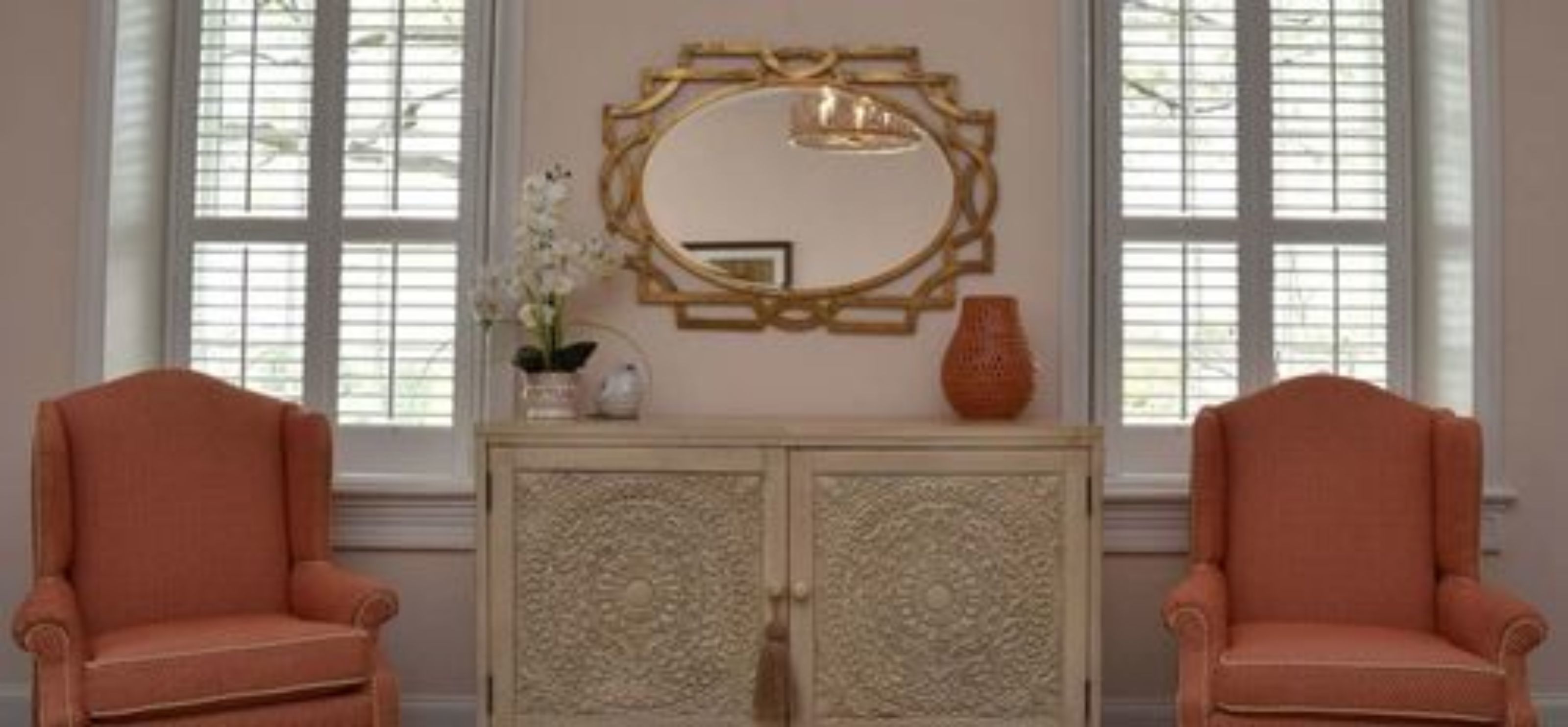 Une pièce comprenant deux fauteuils assortis, un meuble décoratif orné de sculptures complexes et un grand miroir placé au-dessus.