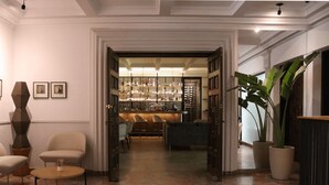 A hotel lobby with a bar area, seating, and a large plant. - Il Buongustaio (San Salvador)
