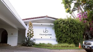 A building with a sign reading "il buongustasio" and a parked car. - Il Buongustaio (San Salvador)