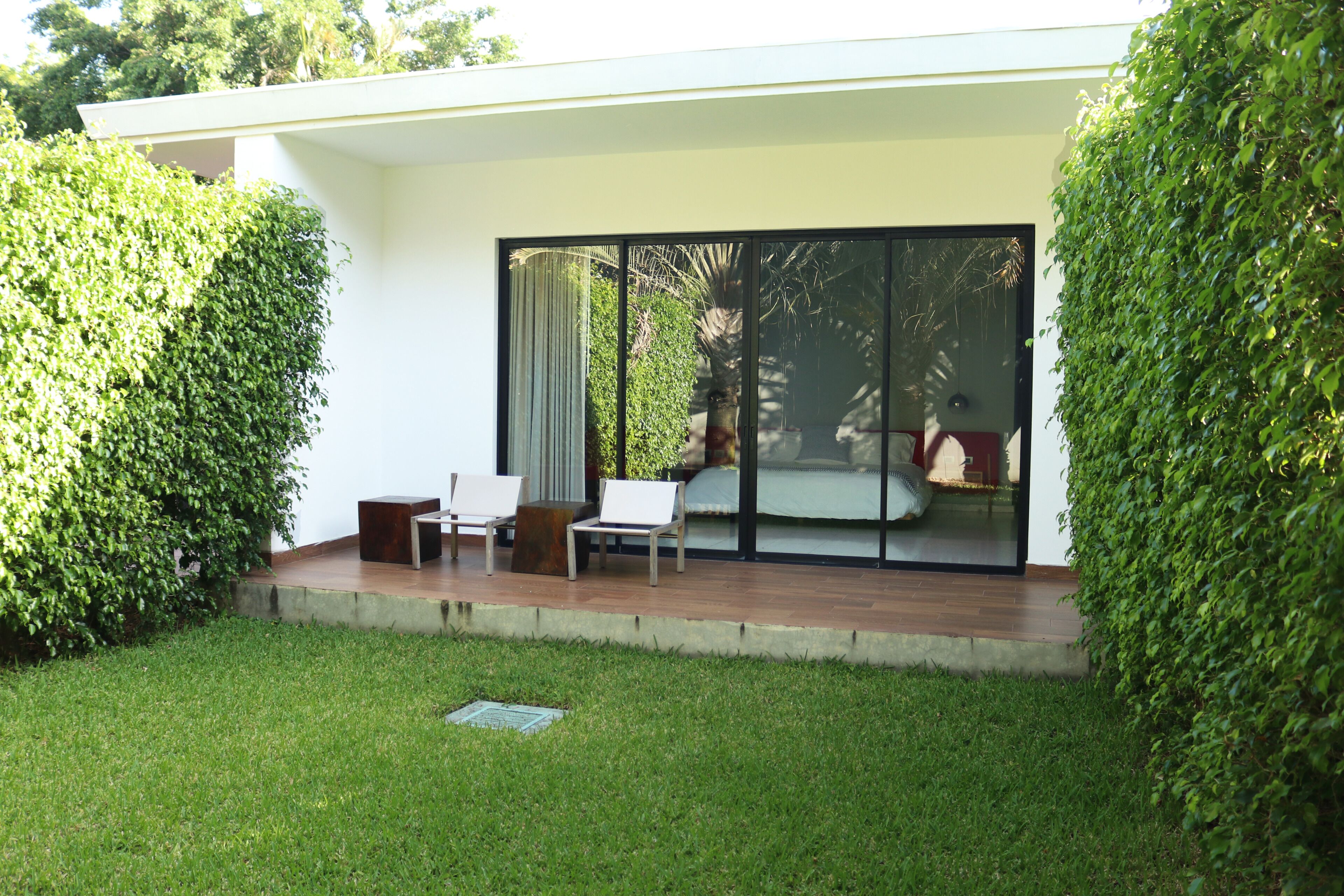 A modern outdoor seating area with a glass door leading to a bedroom.
