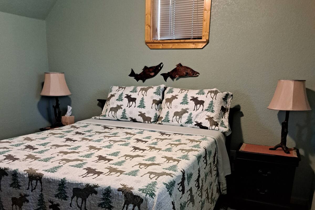 A bedroom with a bed, two bedside tables, a window, and a rug.