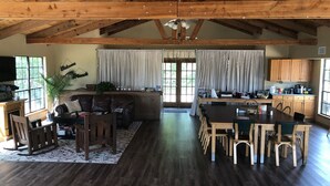 A spacious living area with a wooden ceiling, a dining table, and a kitchen area with wooden cabinets.