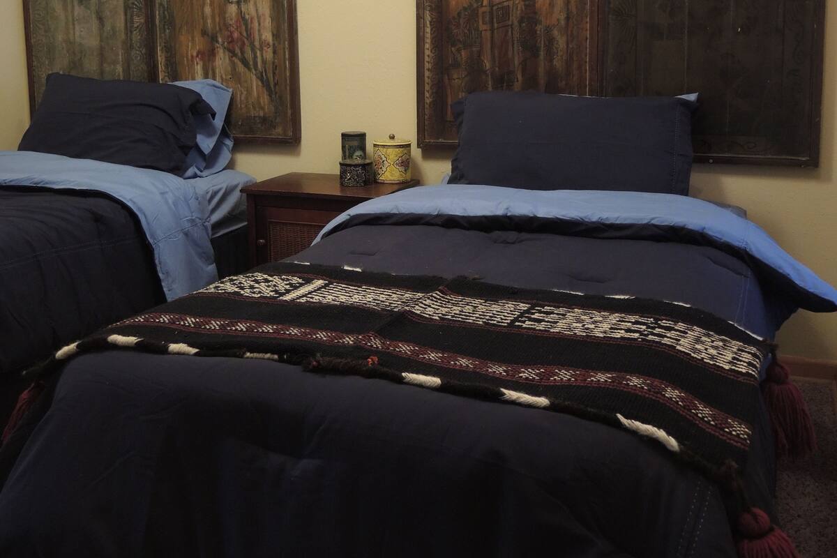 A bedroom with two beds, a decorative horn, and two wooden panels on the wall.