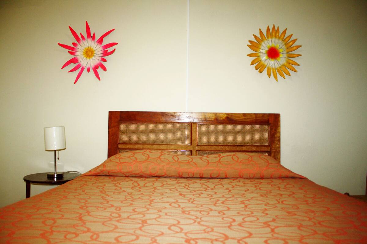 A hotel room with a bed, a nightstand, and two wall-mounted flower decorations.