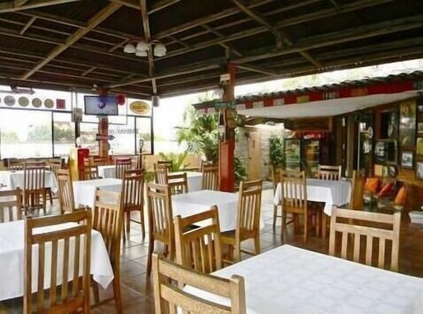 A restaurant with wooden tables and chairs, a TV mounted on the wall, and a view of the outdoors.