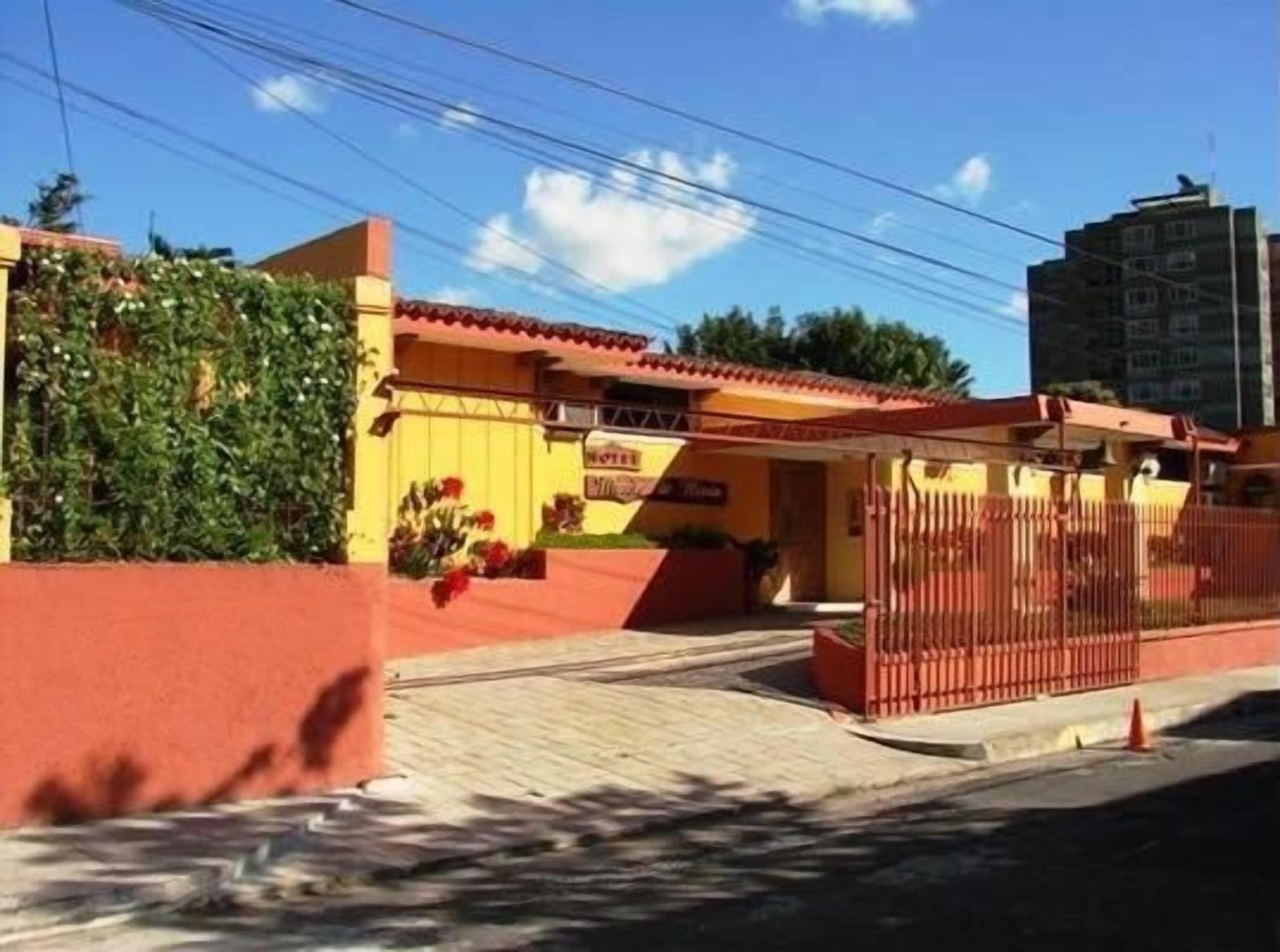 A hotel with a red gate, a yellow facade, and a red roof.