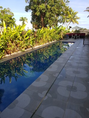 A swimming pool with a tiled deck and surrounding greenery. - Hibiscus Residences Fiji (Nadi)