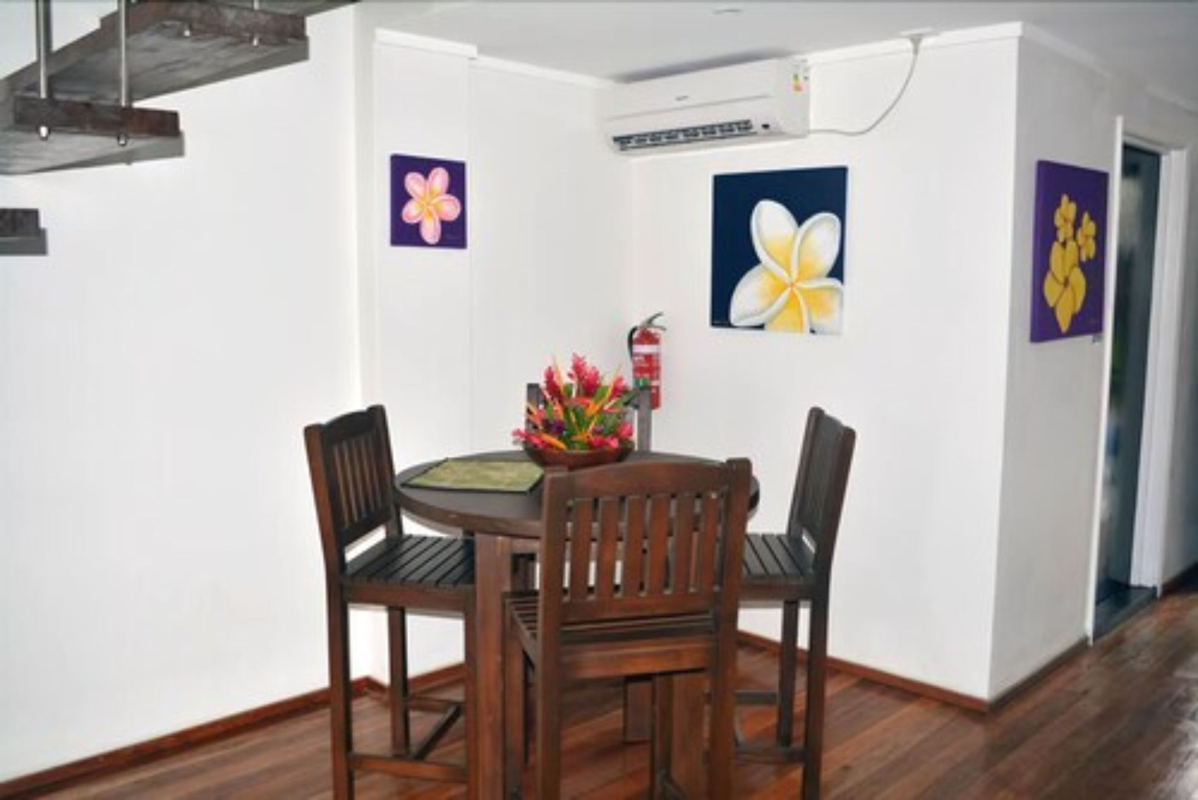 A dining area with a round table, two wooden chairs, and a vase of flowers.