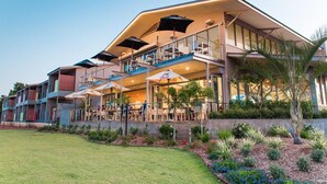 Un hotel de varios pisos con zonas de estar al aire libre, piscina y un jardín bien cuidado.