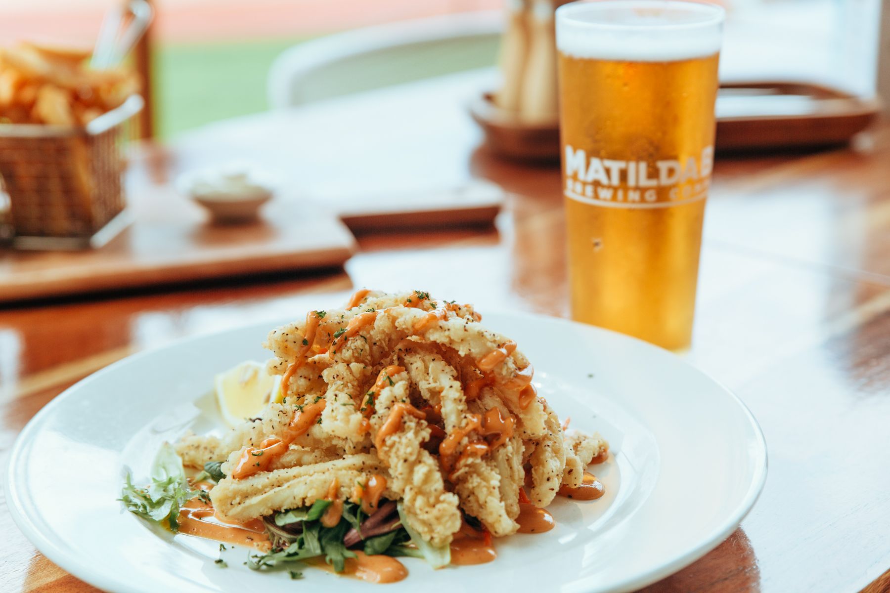 Une assiette de nourriture accompagnée d’une portion de frites et d’une boisson servie dans un verre à l’effigie de la marque.