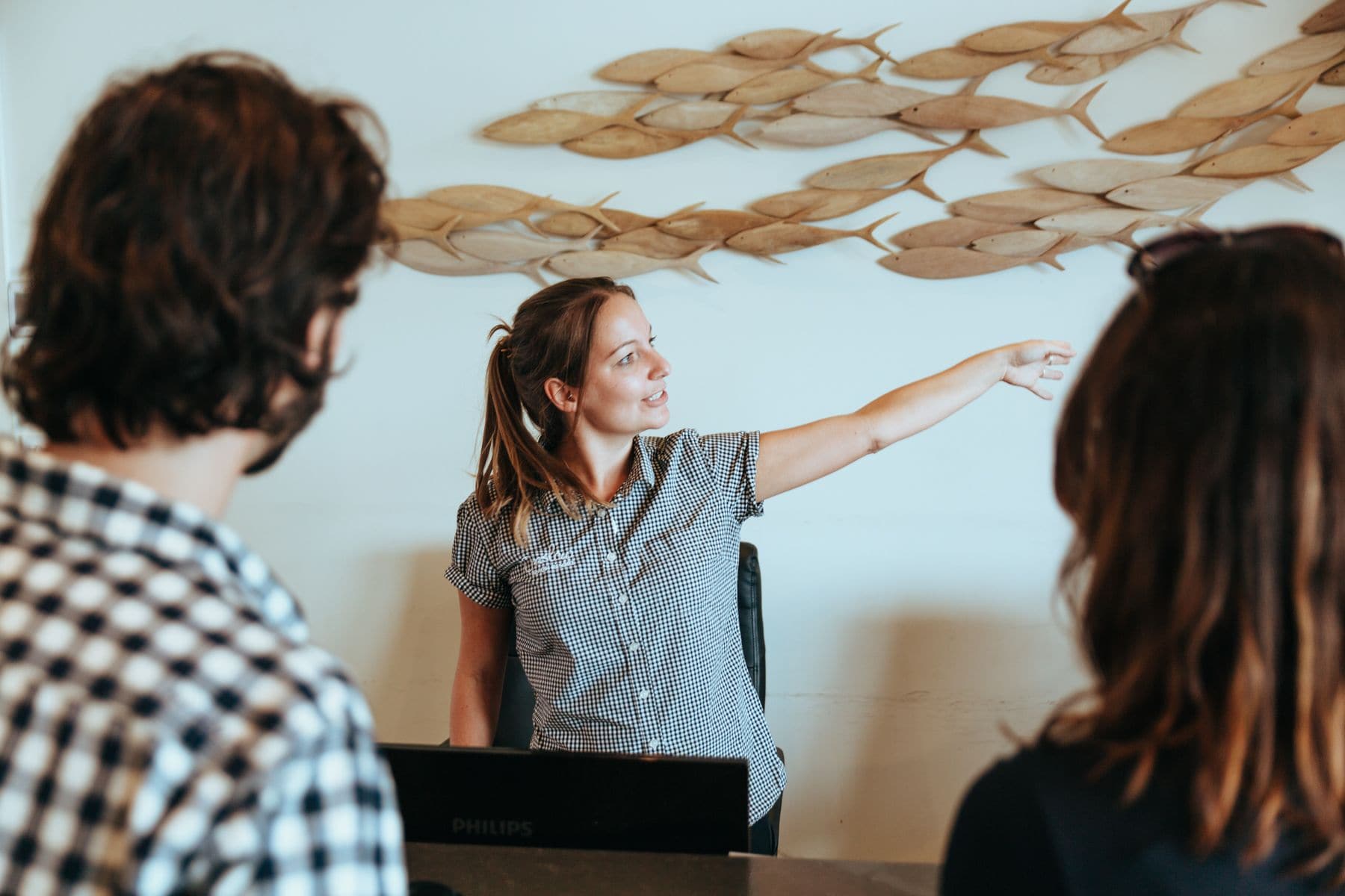 A person pointing at a wall with a fish pattern.