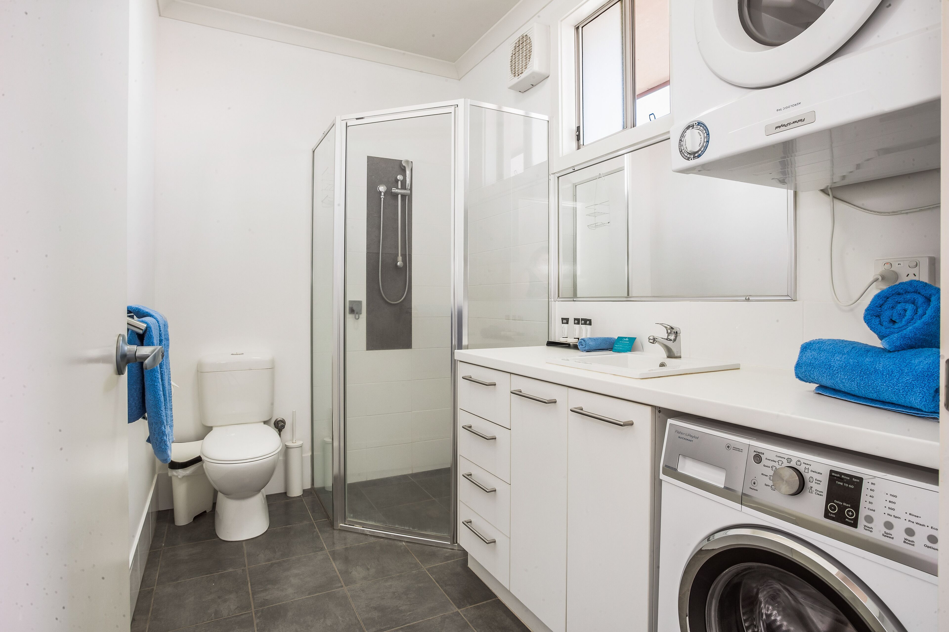 Ein modernes Badezimmer mit Toilette, Dusche und Waschmaschine.