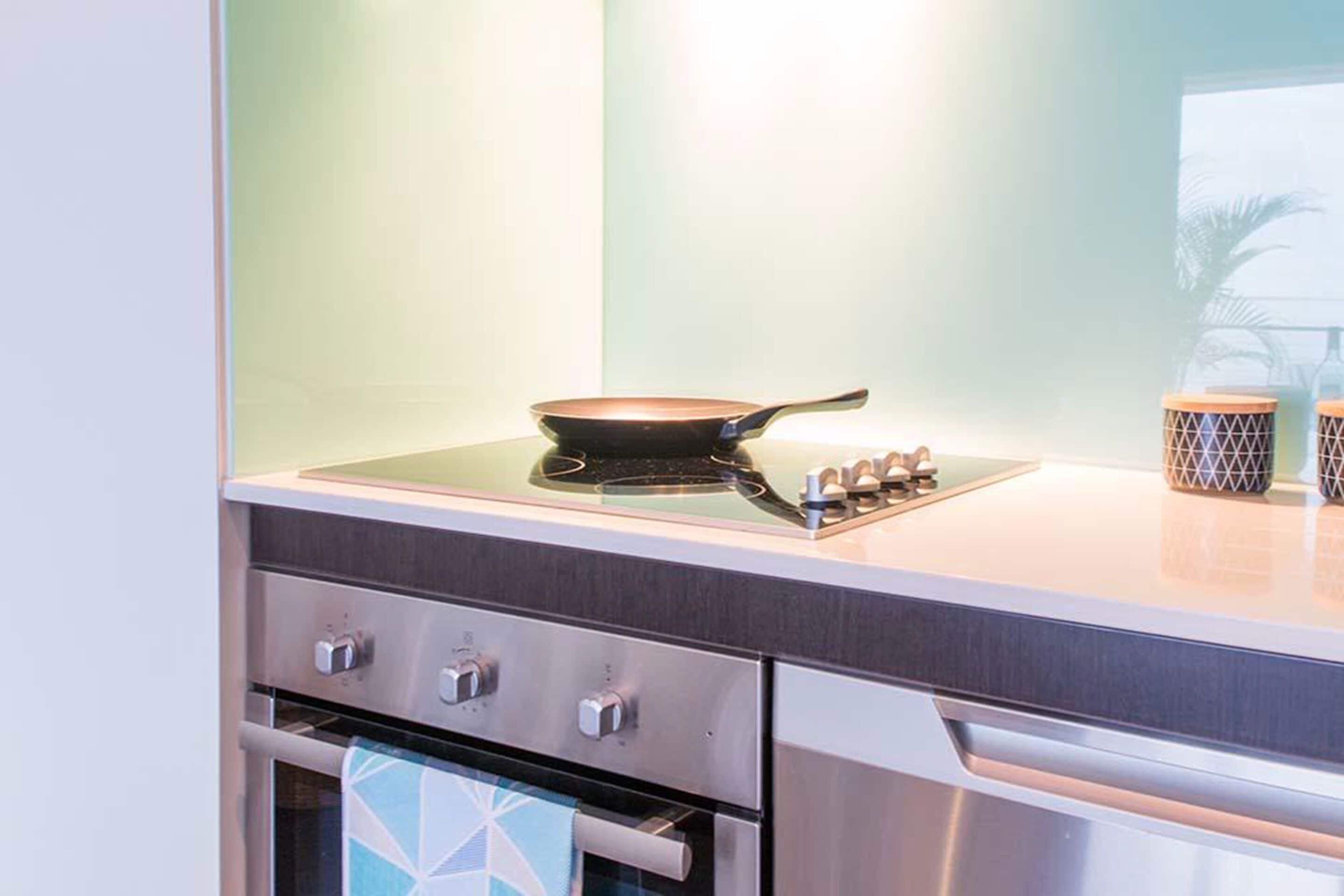 Una cocina con estufa, horno y sartén sobre la encimera.