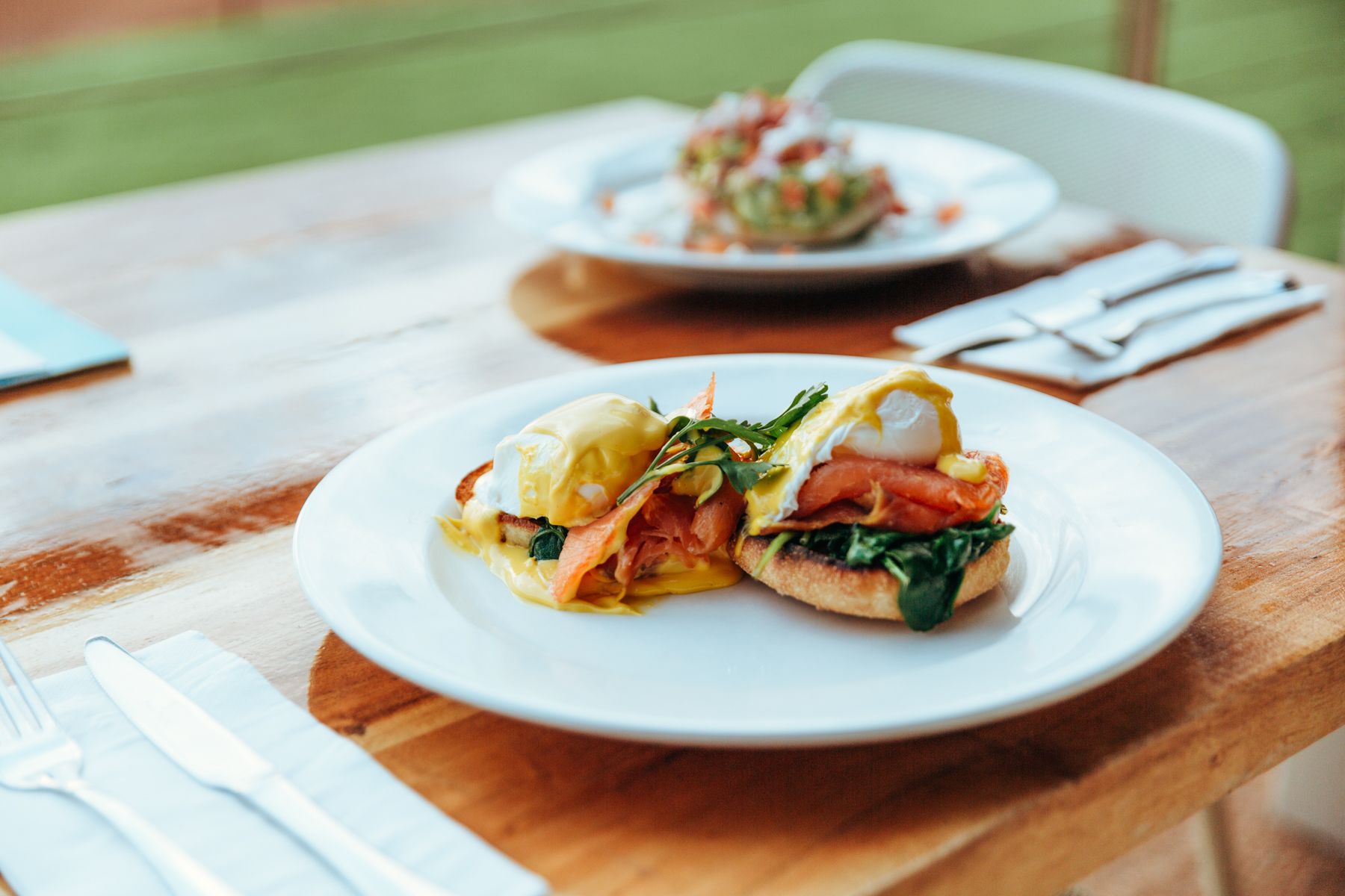 Une table avec deux assiettes de nourriture : l’une contient un sandwich aux œufs, l’autre, une salade.