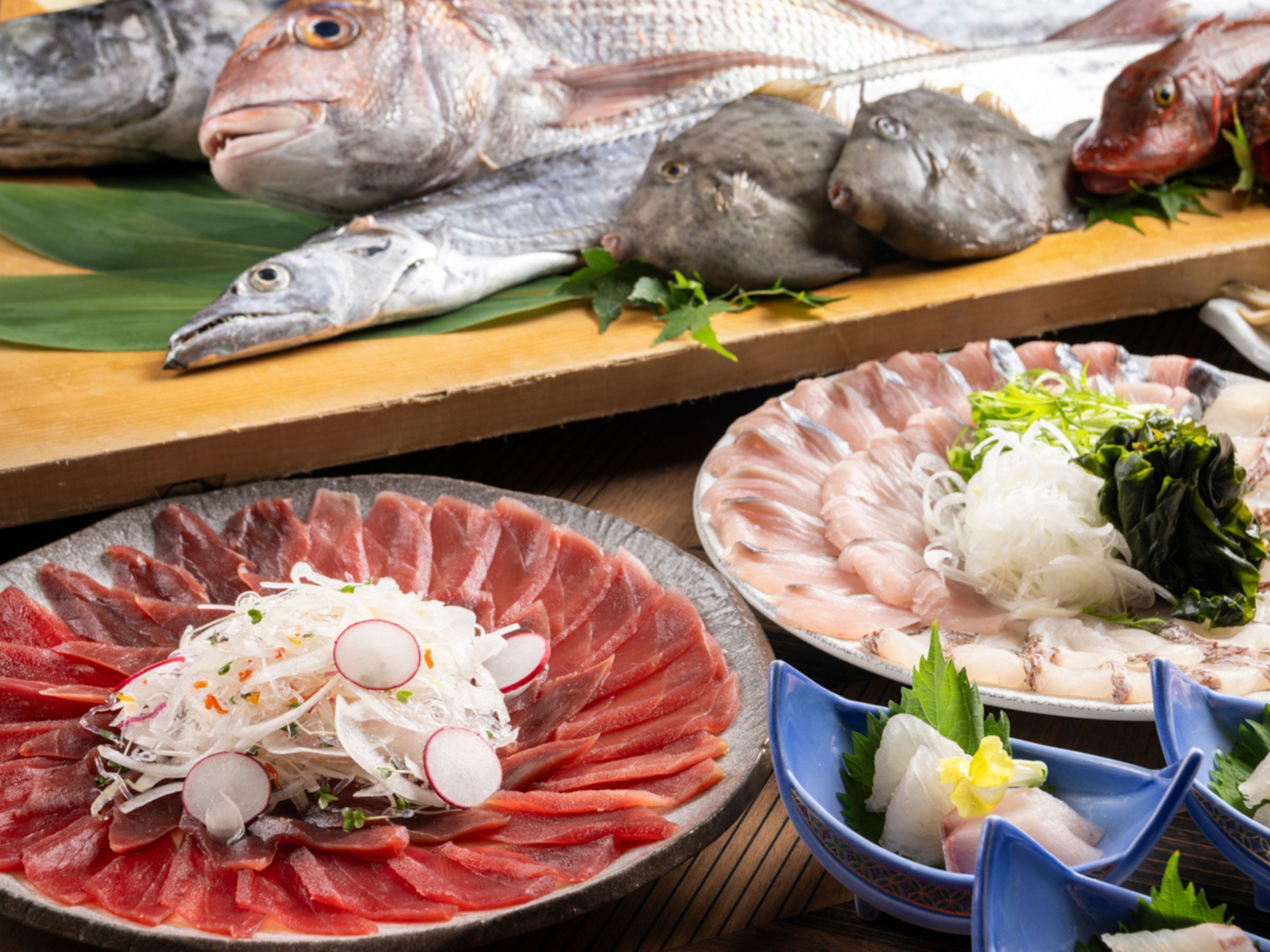 A variety of seafood dishes, including sashimi and raw fish, arranged on wooden tables.
