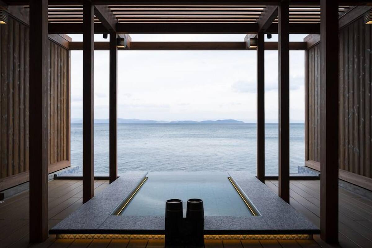 A room with a view of the sea, wooden walls, and a stone floor.