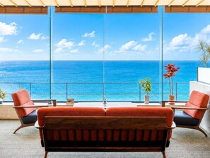 A balcony with a view of the ocean, two red chairs, a wooden sofa, and potted plants. - Awakan (Sumoto)