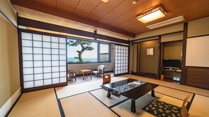 A traditional Japanese room with tatami flooring, a low table, and a view of the sea. - Awakan (Sumoto)