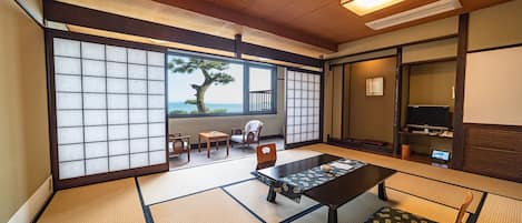 A traditional Japanese room with tatami flooring, a low table, and a view of the sea.