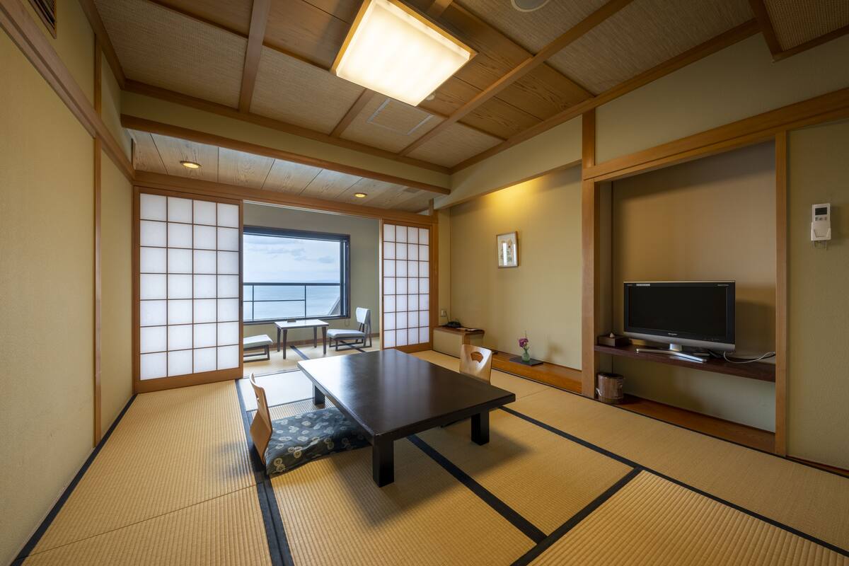 A traditional Japanese room with tatami flooring, a low table, a television, and sliding doors.