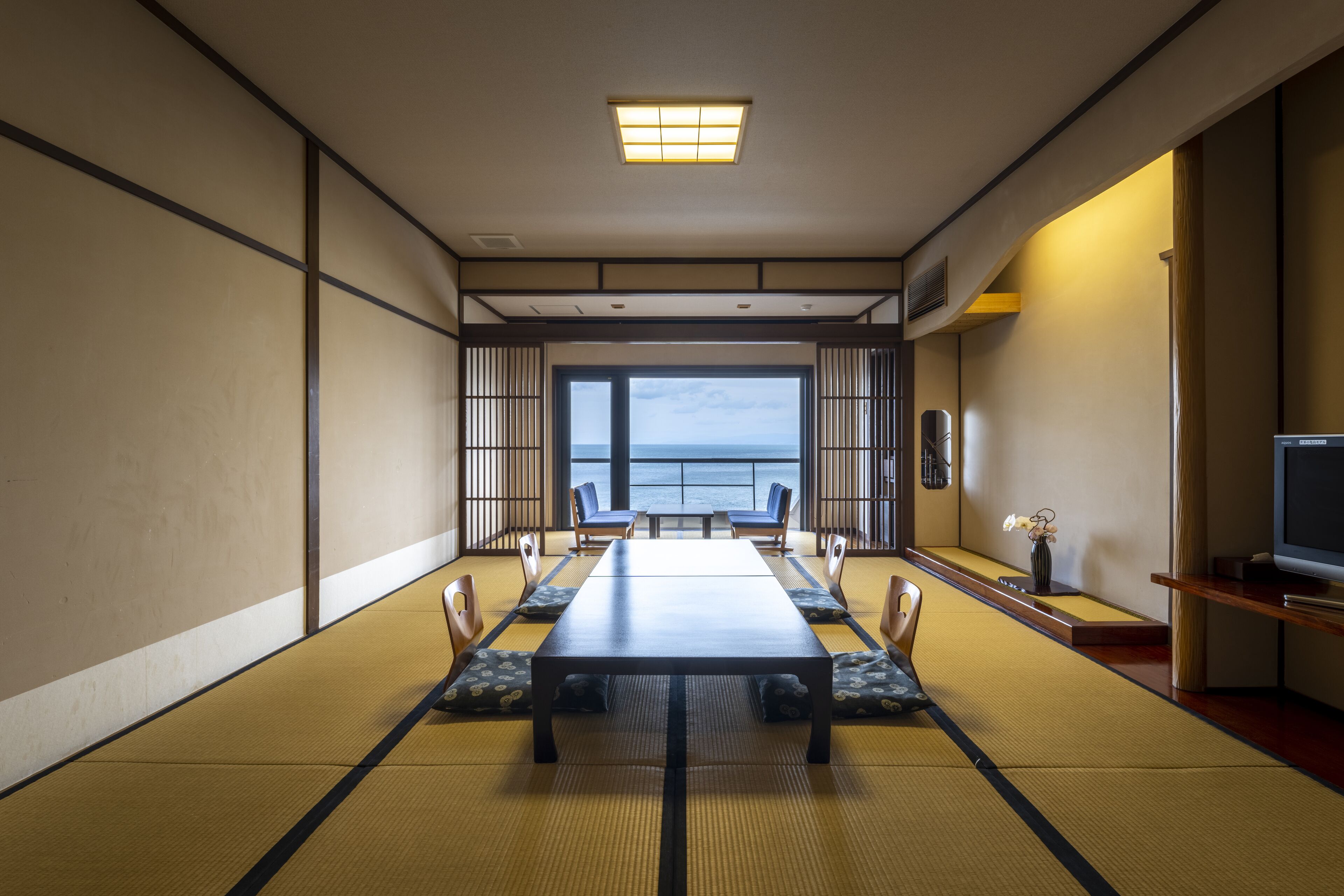 Una habitación japonesa tradicional con suelo de tatami, una mesa baja y vista al mar.