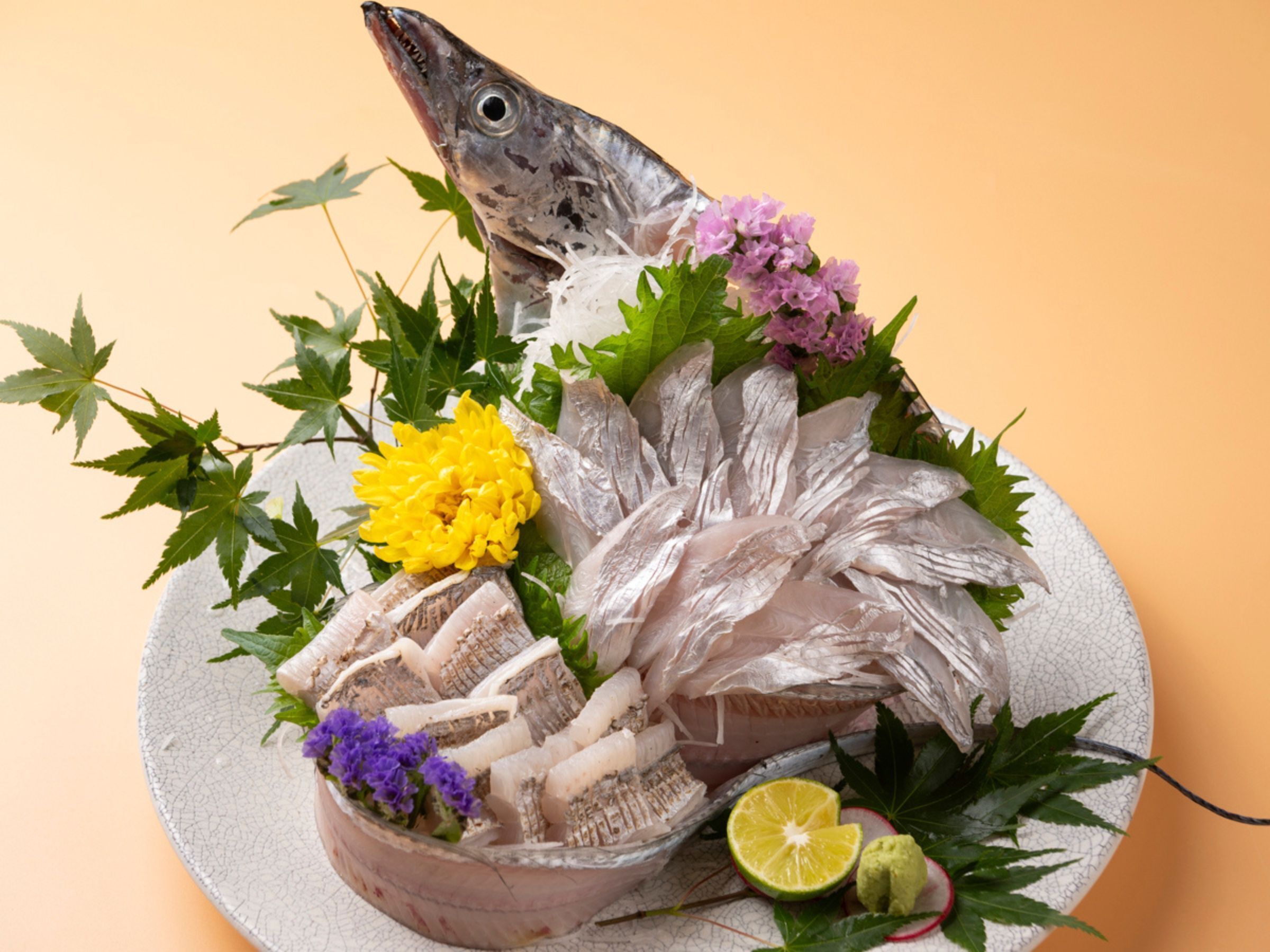Une assiette contenant des filets de poisson, des fleurs et un citron vert.