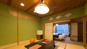 A traditional Japanese room with tatami flooring, a low table, and a bed with a view of the sea. - Awakan (Sumoto)