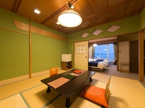 A traditional Japanese room with tatami flooring, a low table, and a bed with a view of the sea. - Awakan (Sumoto)