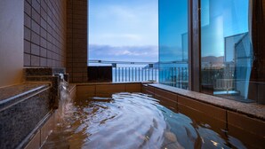 Un jacuzzi con vistas al océano a través de un ventanal grande.