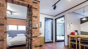 A room with a brick partition, a bed, a wooden table with chairs, and a kitchenette. - Xicun 168 B&B (Seoul)