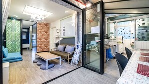 A modern living room with a sofa, a coffee table, and a dining area with a table and chairs. - Xicun 168 B&B (Seoul)