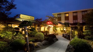 Ein Hotel mit einem gepflegten Garten, einem Weg zum Eingang und einem Schild mit dem Namen 'Yakiniku'.