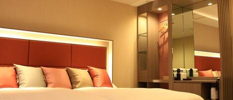 Een hotelkamer met een groot bed, een spiegel en een garderobe.