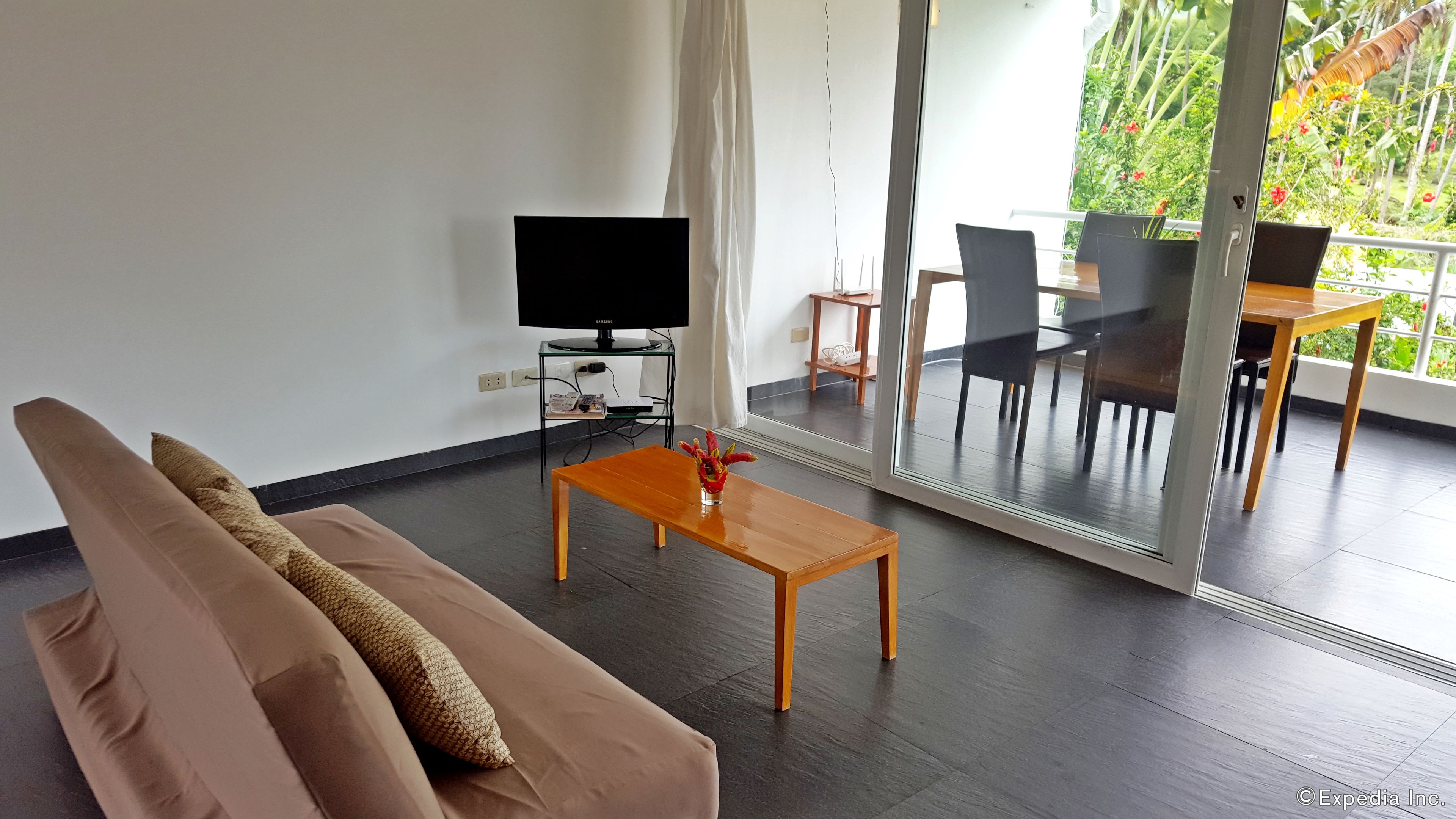 Un salon moderne comprenant un canapé, une table basse, un téléviseur et un coin repas avec des chaises et une table.