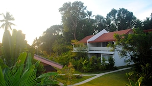 A modern house with a red roof, surrounded by lush greenery and a well-maintained lawn.