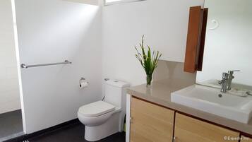 Un baño moderno con inodoro, bidé, lavamanos y espejo.