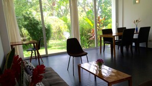 A modern living room with a sofa, a coffee table, and a dining area with chairs and a table.