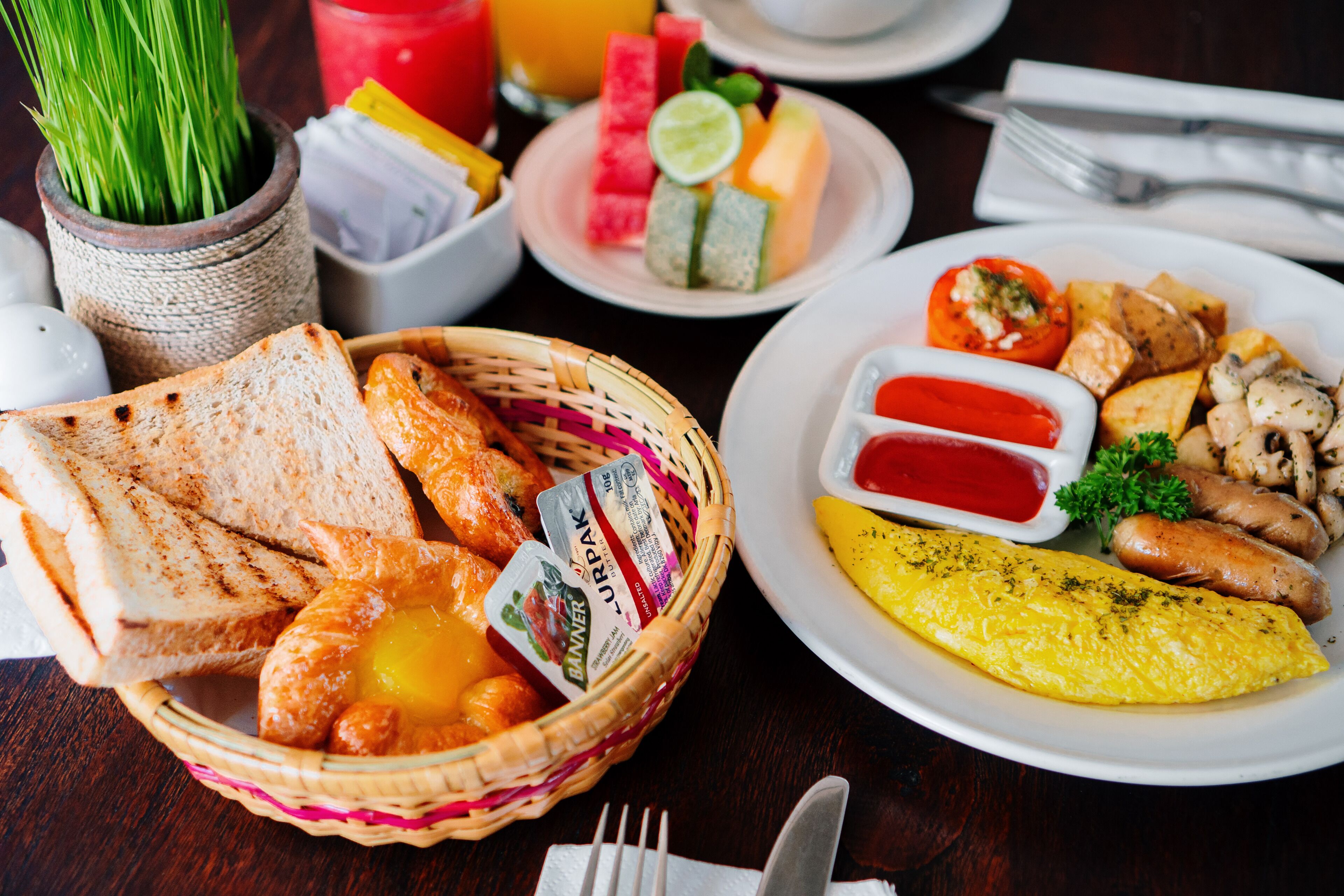 A breakfast setting with toast, eggs, sausages, and a variety of fruits and vegetables.