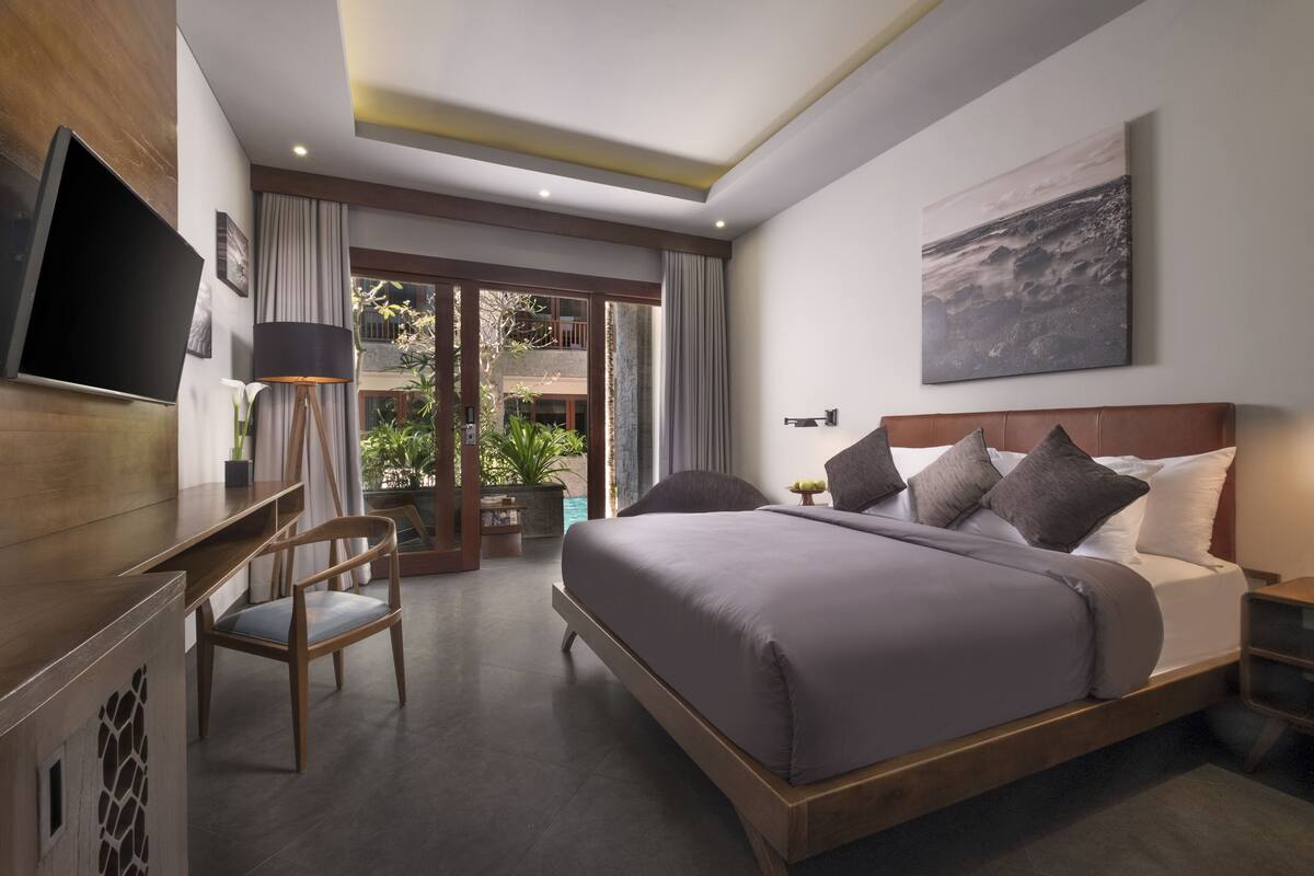 Une chambre d’hôtel moderne dotée d’un grand lit, d’une télévision à écran plat, d’un bureau et offrant une vue sur l’extérieur.